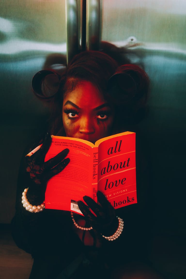 Artistic portrait of woman reading 'All About Love' with dramatic lighting.
